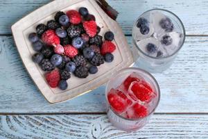 frutas congeladas e cubos de gelo, framboesa e mirtilo na mesa foto