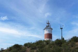 um pequeno farol de pé sobre uma rocha contra o céu azul. foto