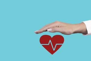 conceito de seguro de saúde, a mão da mulher cobre o símbolo do coração vermelho. copie o espaço. foto