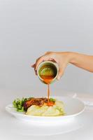 mulher derramando molho em coxinhas de frango assado com purê de batata na mesa. foto