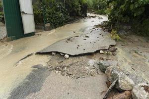 uma estrada destruída após uma inundação e lama com fluxo de água suja. conceito de desastres naturais. foto