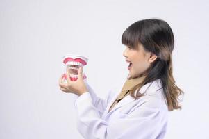 jovem dentista feminina sorrindo sobre estúdio de fundo branco foto