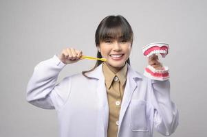 jovem dentista feminina sorrindo sobre estúdio de fundo branco foto