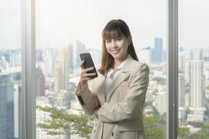 jovem mulher de negócios linda usando telefone inteligente no escritório moderno foto