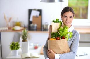 jovem mulher segurando a sacola de compras com legumes em pé