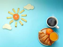 ideia criativa de café da manhã, céu azul da manhã do nascer do sol com refeição de nuvem, frutas laranja, açúcar de manteiga de pão crocante, pão branco nublado, croissant, café preto quente e suco de laranja. acordar em dia mais brilhante foto