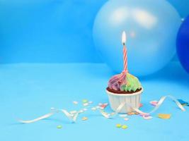 doce cupcake e vela de arco sobre fundo azul com espaço de cópia. feliz festa de aniversário foto