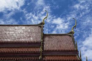 telhado vermelho de um templo tailandês com ápice de empena é uma delicada arte tailandesa criada por artesãos qualificados. e em todos os templos tailandeses é a mesma arte no céu azul em um dia ensolarado. foto