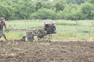 os agricultores estão preparando o solo para o cultivo de hortaliças locais usando tratores de passeio e o trabalho de agricultores na tailândia rural que usam mão de obra e energia para melhorar a terra. foto