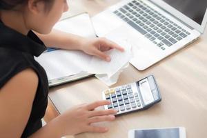 closeup mão mulher calculando despesas domésticas e caderno de escrita na mesa, menina verificando conta e estresse e nota, preocupação feminina dívida e imposto, finanças e conceito de negócios. foto