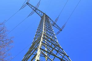 vista de perto em um grande poste de energia transportando eletricidade em uma área rural foto