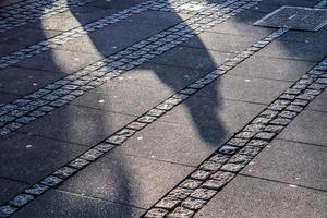 sombras de pessoas em uma área comercial europeia em um terreno de paralelepípedos foto