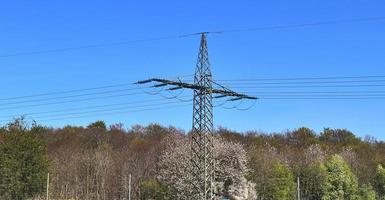 vista de perto em um grande poste de energia transportando eletricidade em uma área rural foto