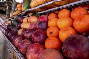 pilha de romãs frescas e laranjas para venda na banca do mercado foto