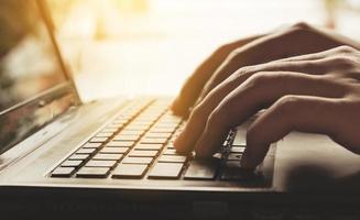 Feche a mão usando computador e teclado digitando na internet online.