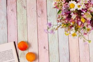 livro de damascos e flores na mesa colorida, copie o espaço foto