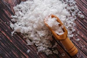 flor de sal, é um sal que se forma como uma crosta fina e delicada na superfície da água do mar na colher de madeira sobre fundo de madeira. foto