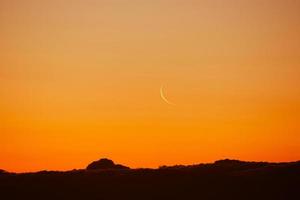 lua minguante no céu colorido. satélite da terra sobre a cidade em raios de sol. foto