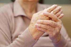 mulher idosa asiática ou idosa está amassando as mãos da dor em casa. saúde, amor, cuidado, incentivo e empatia. foto
