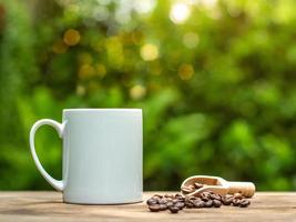 xícara de café e grãos de café em uma velha mesa de madeira, caneca de cerâmica branca. foto