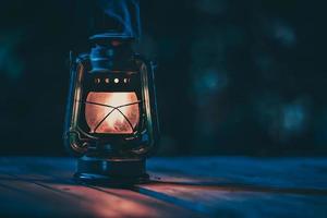 lâmpada de querosene antiga com luzes no chão de madeira no gramado à noite foto