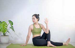 mulher fazendo ioga no tapete de ioga verde para meditar e se exercitar em casa. foto