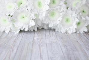 flores de crisântemos brancos delicados em um fundo branco de madeira foto