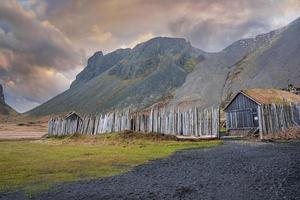 casas viking cercadas por cerca de madeira sob a montanha vestrahorn ao pôr do sol foto