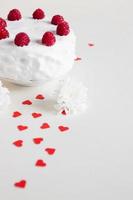 bolo branco com framboesas e corações vermelhos