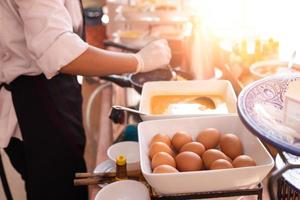 ovos preparados em close-up fazem omeletes no café da manhã com o chef cozinhando ao fundo foto