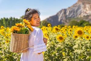 meninas viajam em campos de girassóis amarelos florescendo na temporada de verão na fazenda de girassóis e outras flores foto