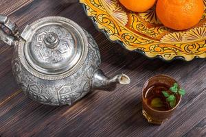chá marroquino com hortelã, chaleira e prato com ornamento tradicional foto