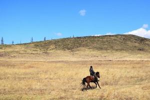 um cavaleiro monta um cavalo através de um vale montanhoso foto