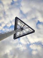 vista de baixo para cima em um sinal triangular alto de um shopping center no céu azul com fundo de nuvens brancas foto