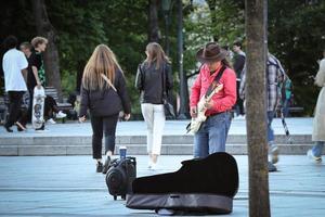 Vilnius, Lituânia. 06 de junho de 2022 - músico de rua de camisa vermelha e chapéu de cowboy tocando violão na rua foto