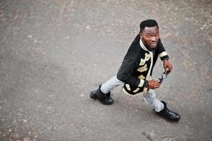 mega homem africano elegante em pose de jaqueta tradicional. cara negro na moda em óculos de sol. foto