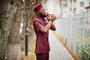 retrato de militar americano africano em uniforme vermelho, sungalasses e boina. capitão fuma charuto. foto