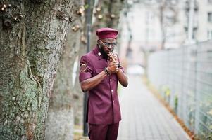 retrato de militar americano africano em uniforme vermelho, sungalasses e boina. capitão fuma charuto. foto