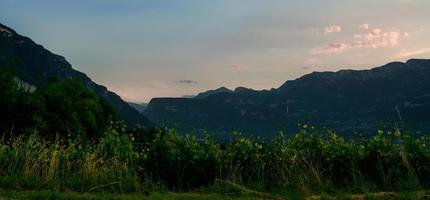 pôr do sol na zona rural com montanhas ao fundo, atrás de vinhas e terras, céu nublado laranja antes da noite depois que o sol se instalou foto