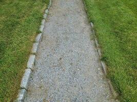 caminho de pedra ou cascalho cinza com grama verde ou gramado foto