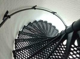 escada em espiral de metal de ferro preto e parede branca no farol foto