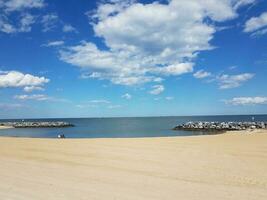 areia e pedras e água e nuvens na praia foto