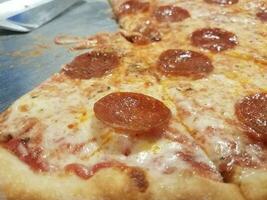 queijo gorduroso e pizza de calabresa na bandeja de metal com espátula foto