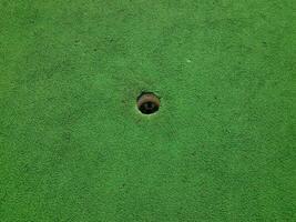 buraco no campo de golfe em miniatura com grama artificial verde foto