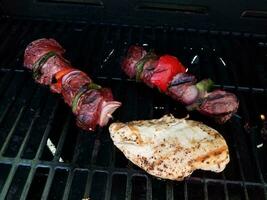 kebob de carne com cebola e pimentão no palito na grelha com frango foto