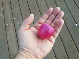 mão segurando casca de ovo rosa com confete no deck de madeira foto