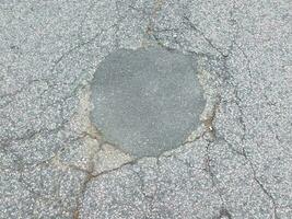 buraco reparado no asfalto preto com rachaduras foto