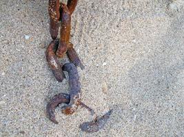 corrente enferrujada na praia de areia. foto