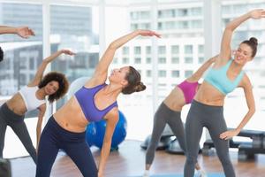 desportivas mulheres esticando as mãos na aula de yoga