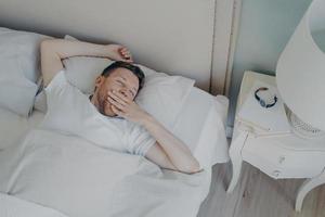 alegre jovem atraente acordando de manhã na cama foto